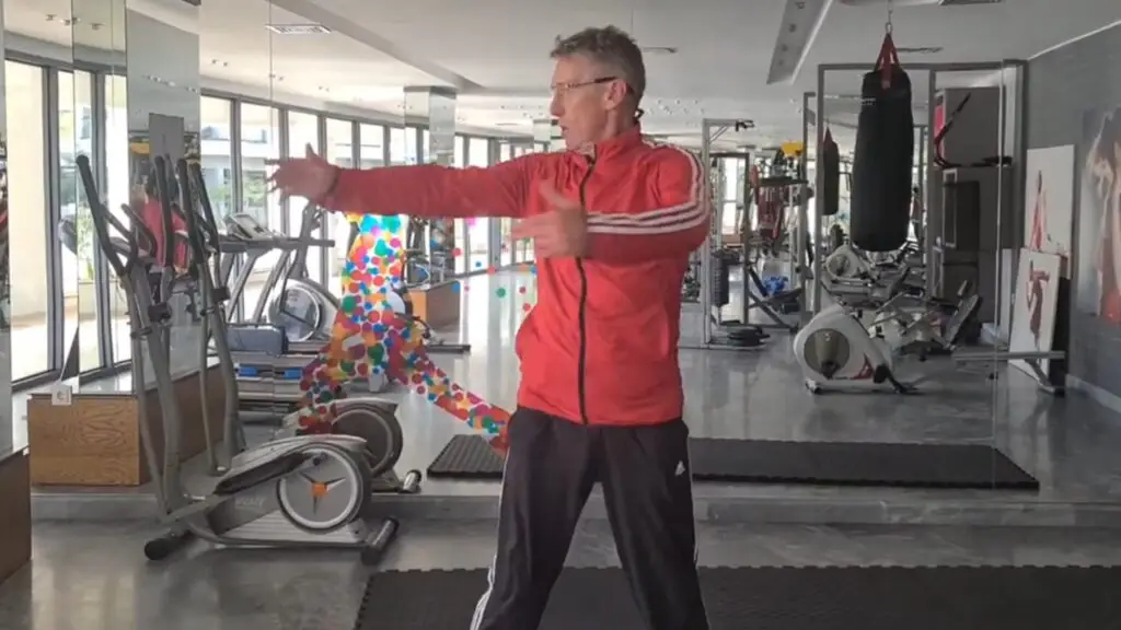 A still image from one of many videos showing Mojoh giving gym coaching & training lessons - the Chest Spin - one of the best chest exercises for warming up prior to heavier chest exercises, used in conjunction with the Cross Arm Swing and the Forward Arm Rotation